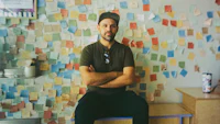 a man sitting in front of a wall covered with post it notes