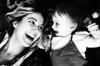 a black and white photo of a woman laughing with a baby