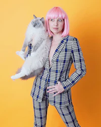 a woman in a plaid suit holding a cat