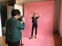 a woman is posing for a photo in front of a pink backdrop